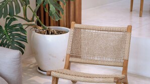 A wicker chair with a woven backrest and wooden legs, positioned on a patterned rug. - Villa Kayu Pererenan (Canggu)