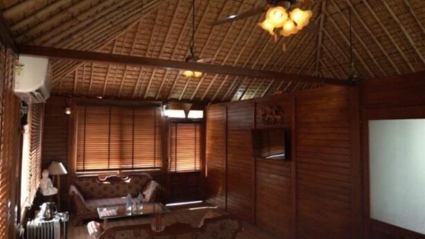Una stanza con soffitto in bambù, pareti in legno, un divano, un tavolo e una televisione.