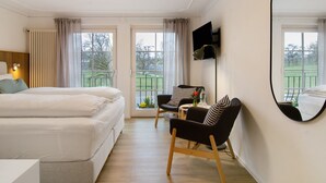 A hotel room with two beds, a desk, a chair, a TV, and large windows. - Room 'Meersburg' with shared terrace and Wi-Fi (Salem)