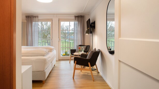 A bedroom with a bed, a desk, two chairs, a mirror, and a window with curtains. - Room 'Meersburg' with shared terrace and Wi-Fi (Salem)