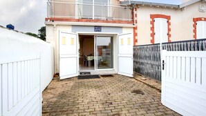 A two-story building with a balcony, a door with glass panels, and a paved entrance area. - Ker Zelia by Interhome (La Bernerie-en Retz)