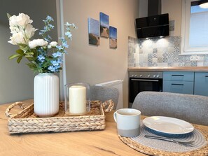 A kitchen with a microwave, stove, and tiled backsplash. There's a vase with flowers, a candle, and a tray with a mug and plate.
