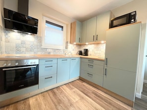 A modern kitchen with a Bosch oven, a microwave, and a coffee maker.