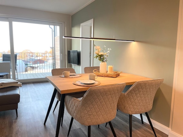 A dining area with a table, chairs, and a TV mounted on the wall.