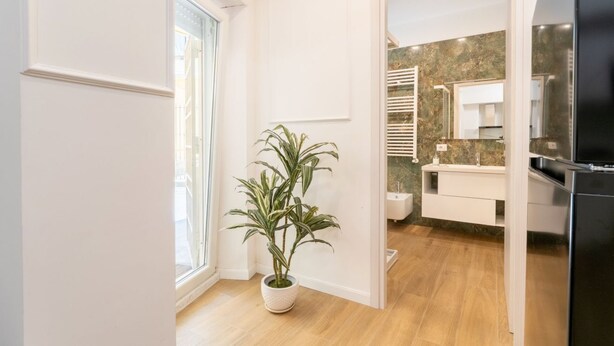 Een moderne badkamer met een marmeren aanrecht, een witte wastafel en een zwarte koelkast.