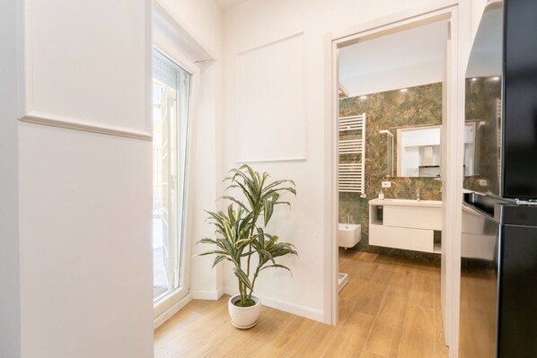Une salle de bain moderne avec un comptoir en marbre, un lavabo blanc et un réfrigérateur noir.