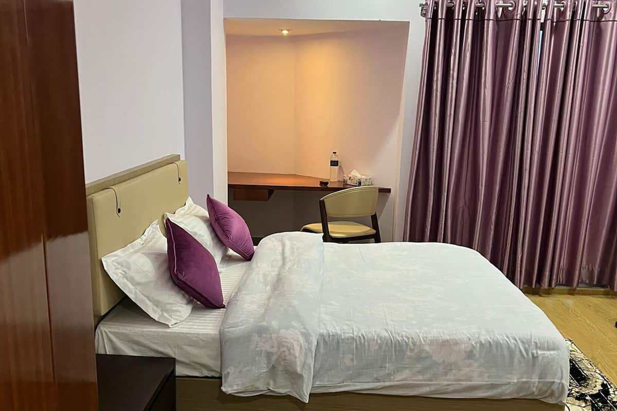 Un dormitorio con cama, escritorio, silla y una mesita.