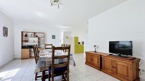 Un espace repas comprenant une table, des chaises, un téléviseur et un meuble en bois.