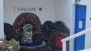 Un mur de pierre surmonté d’une arche ornée de mosaïques et d’une enseigne sur laquelle on peut lire : « Plaisir ».