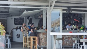 Un espace bar extérieur avec un jeu de fléchettes, des tabourets en bois et un comptoir.