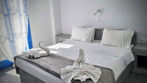 Une chambre à coucher avec un lit, deux tables de chevet, une lampe fixée au mur et une fenêtre avec des rideaux bleus.