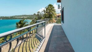 A balcony with a view of the sea and palm trees.