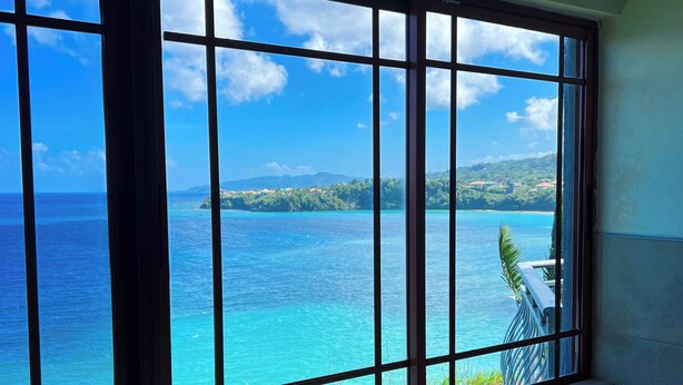 A bathroom with a large bathtub and a view of a turquoise sea and a small island.
