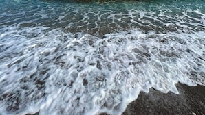 A beach with clear water and waves.