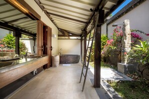 Ein modernes Badezimmer mit einem Holzwaschtisch, einer großzügigen Badewanne und einer Steinwand mit Pflanzen.