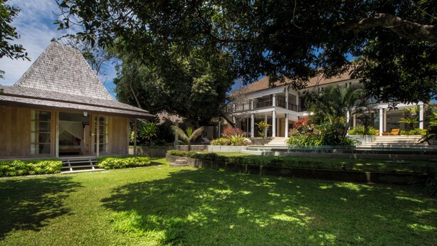 A building with a sloped roof, surrounded by well-maintained grass and trees. - Akilea villas (Pecatu)