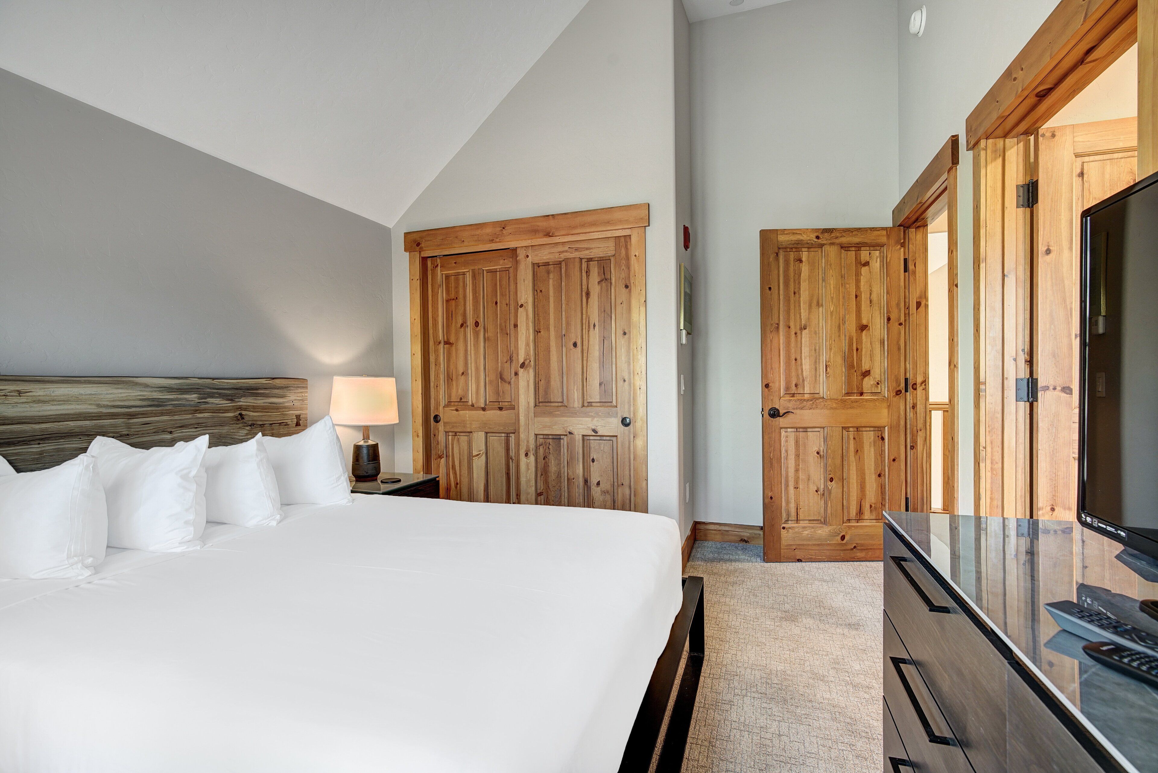Habitación de hotel con una cama grande, armario de madera y televisor de pantalla plana.