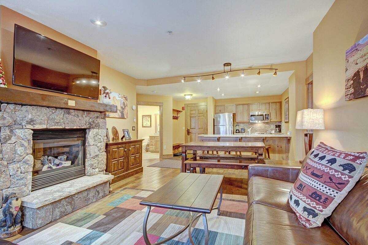 A spacious living area with a stone fireplace, a wooden dining table, and a leather sofa.