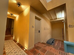 A hallway with a patterned rug, a door labeled "AUTENTHICO 020", and a blue bench. - Autenthico Provenza Hotel Medellin (Medellín)