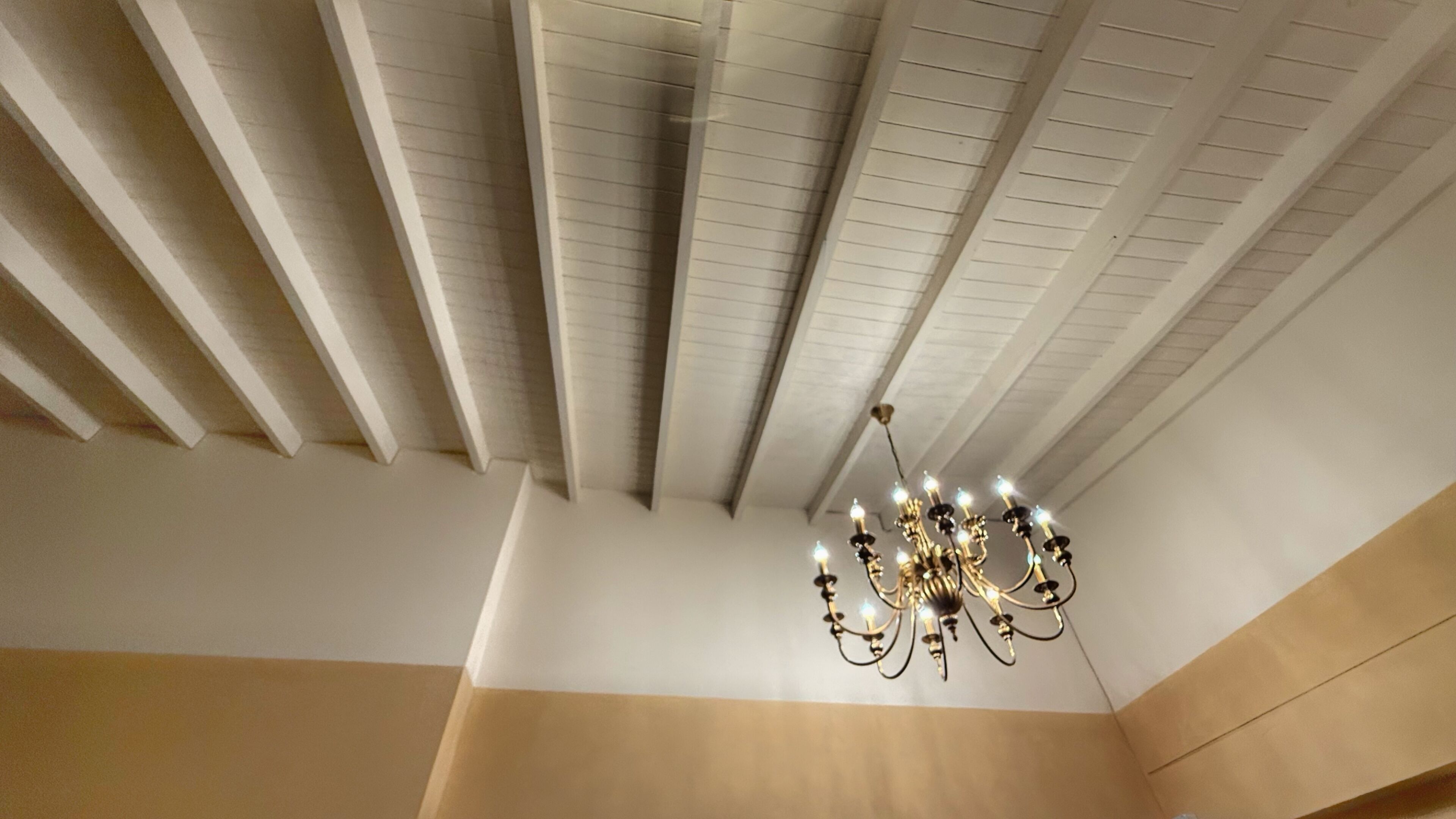 A room with a high ceiling, white walls, and a chandelier.