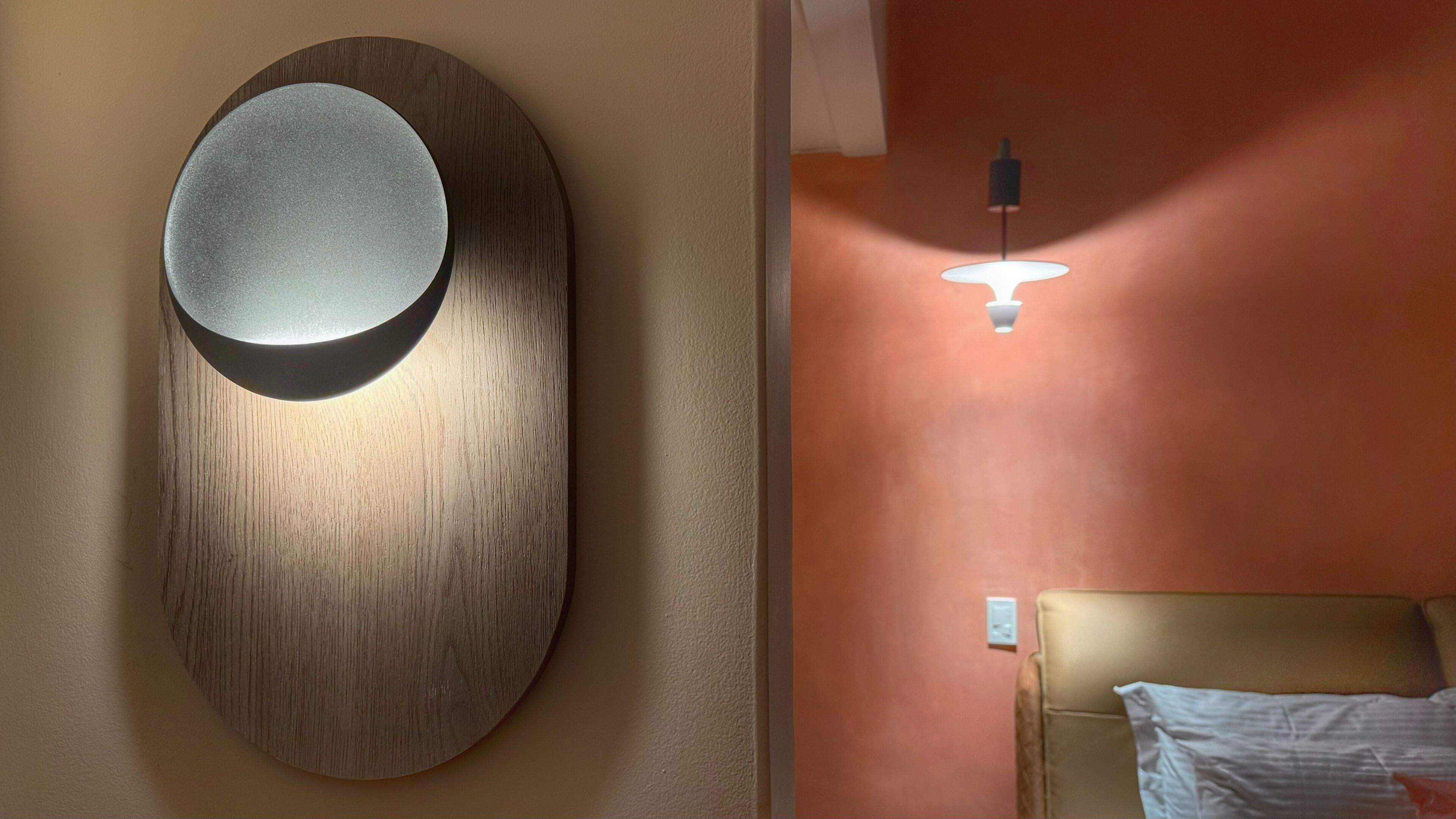 Una habitación moderna con una lámpara de pared circular y una mesita de noche con lámpara.