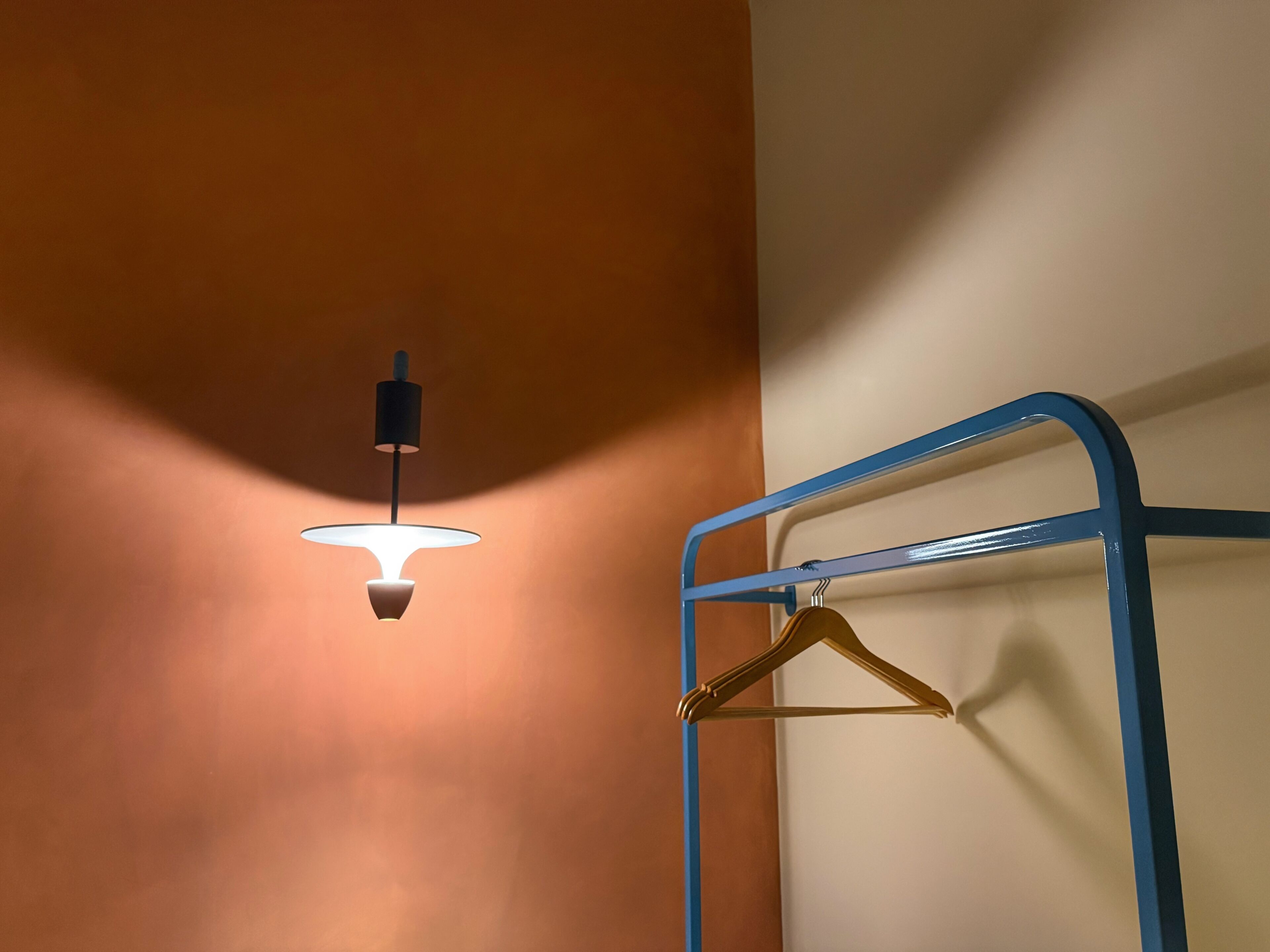 A wall-mounted light fixture and a blue metal rack with a gold hanger.