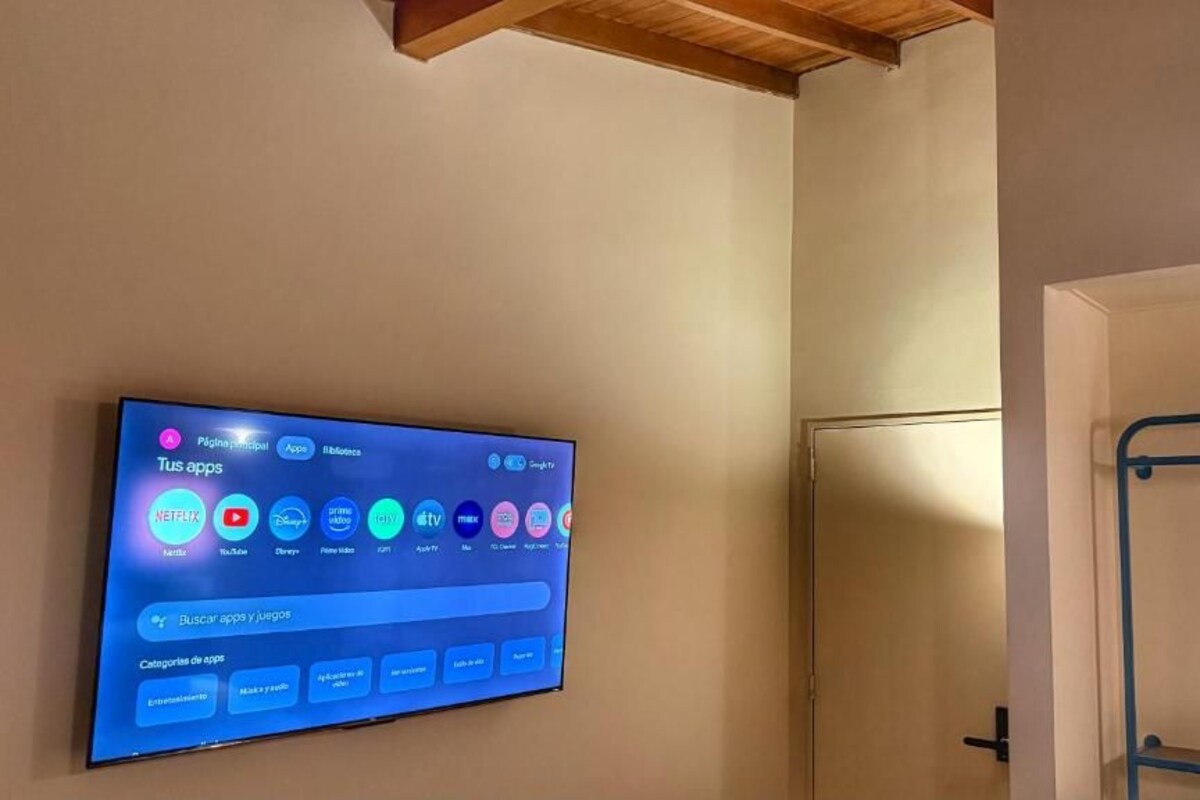 En platt-TV som är monterad på en vägg och visar ett gränssnitt för en streaming-app, med olika kategorier och appar.