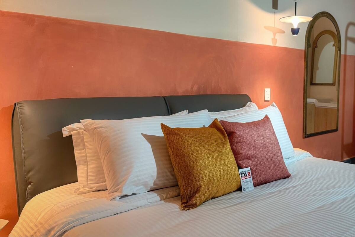 Une chambre d’hôtel comprenant un lit, une table de chevet, un miroir et une salle de bain.
