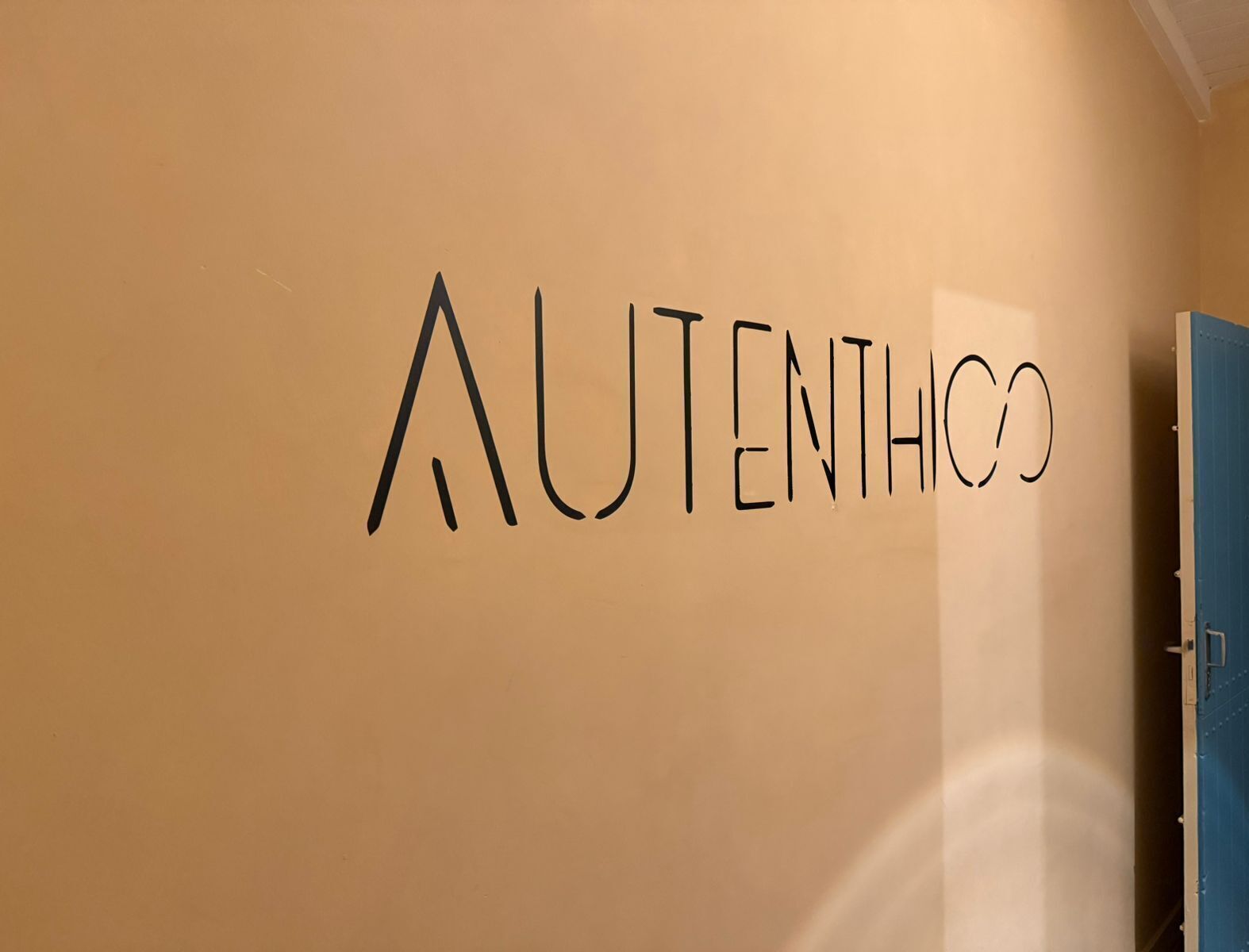 Een muur met de tekst 'AUTHENTICO' in een stijlvol lettertype.