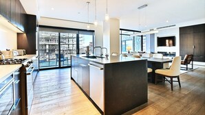 Una cocina moderna con una isla central, electrodomésticos de acero inoxidable y un amplio ventanal con vistas a un paisaje urbano.