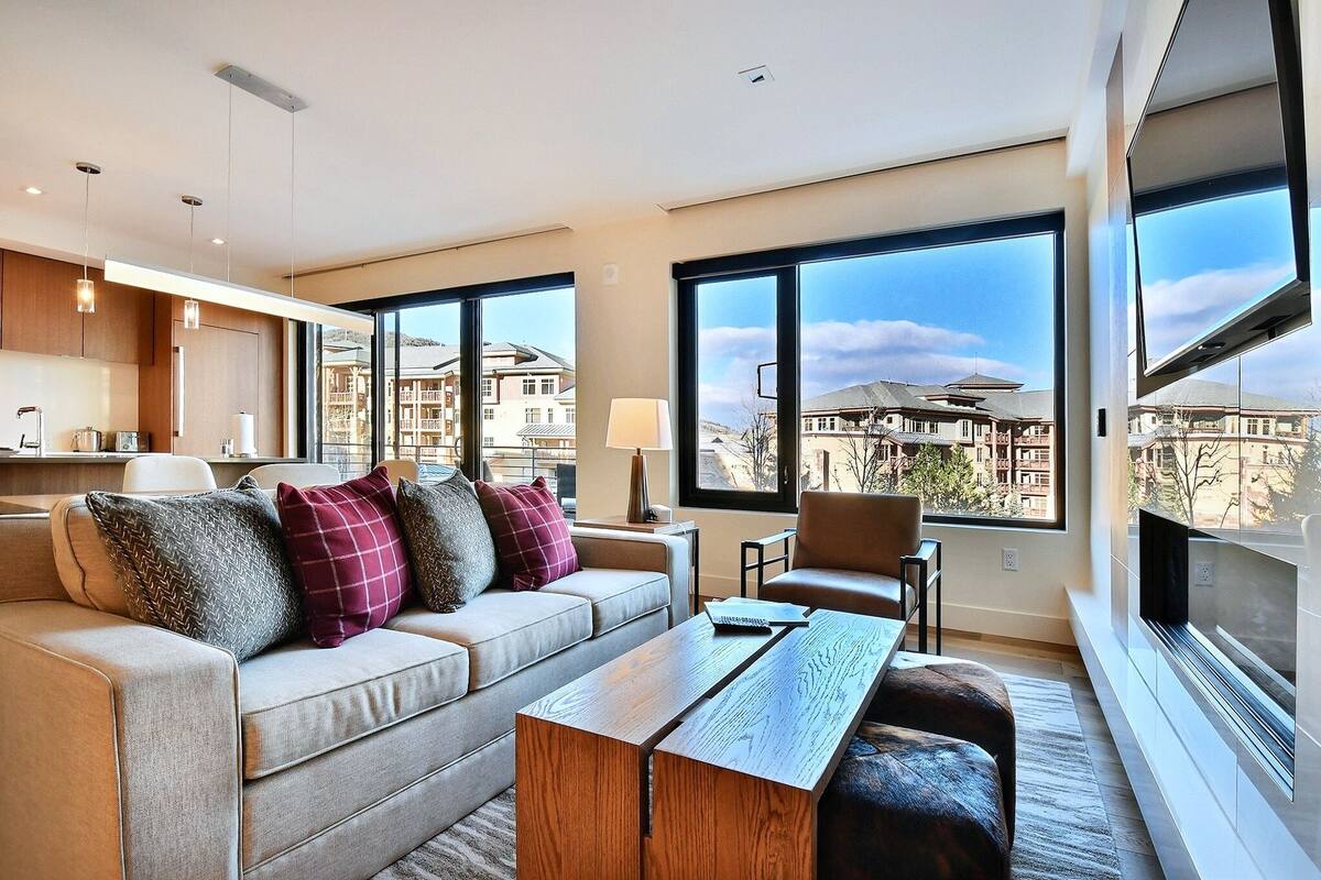 Ein modernes Wohnzimmer mit einer Couch, einem Couchtisch und großen Fenstern mit Blick auf die Stadt.