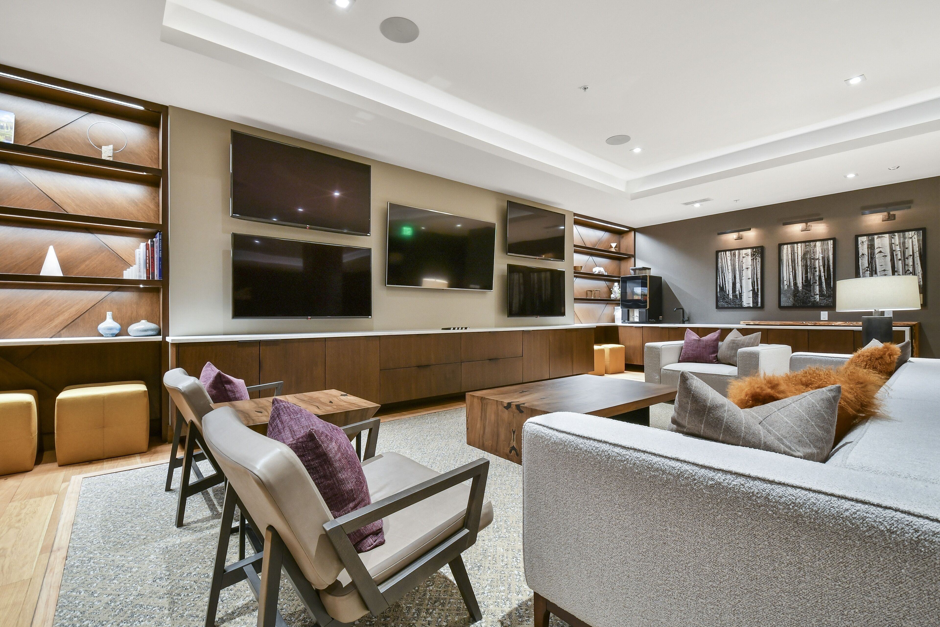 Una sala de estar moderna con sofá, sillones, una mesa de centro y un televisor montado en la pared.