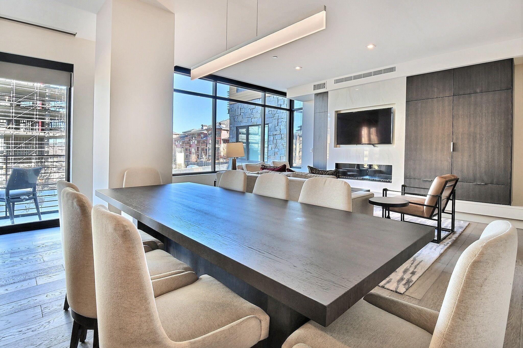 A modern conference room with a large table, comfortable chairs, a sofa, and a view of the city through large windows.