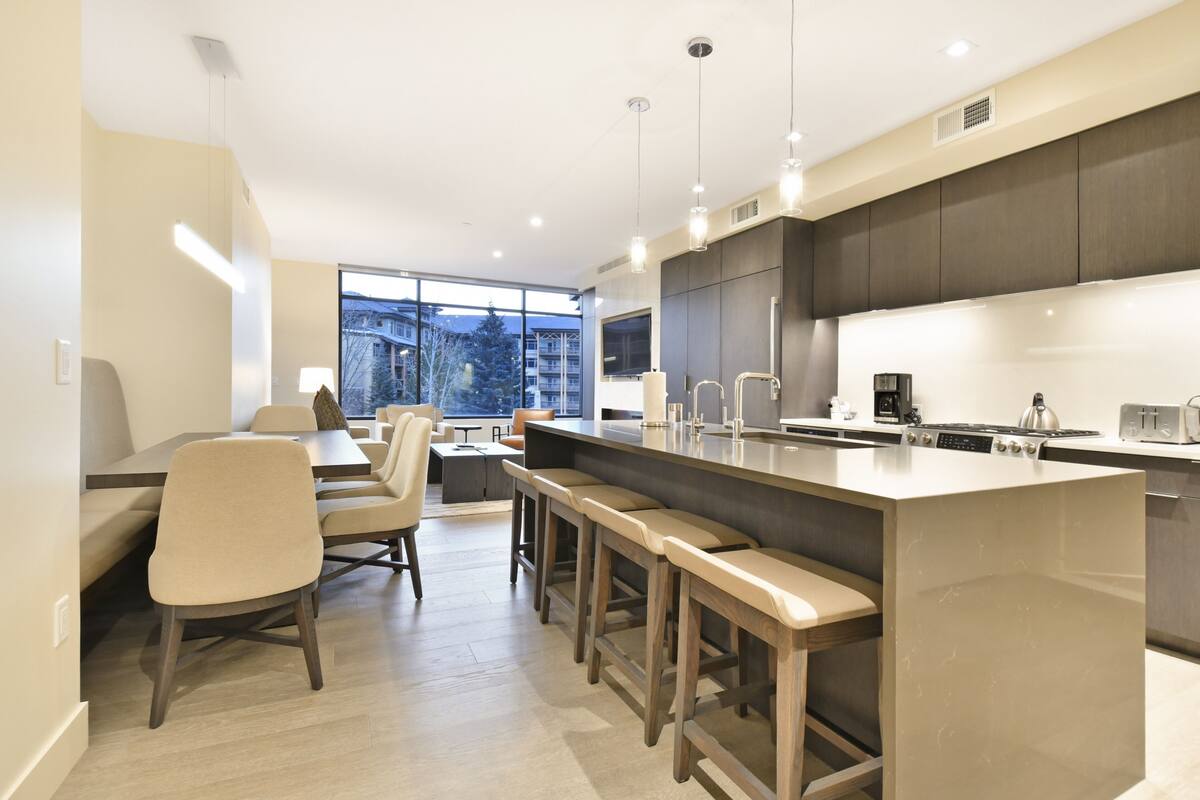 Eine moderne Küche mit einer großen Kochinsel, Barhocker und einem Essbereich mit Tisch und Stühlen.