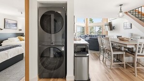 Un apartament modern amb rentadora i assecadora, zona de menjador i saló amb sofà i televisor.