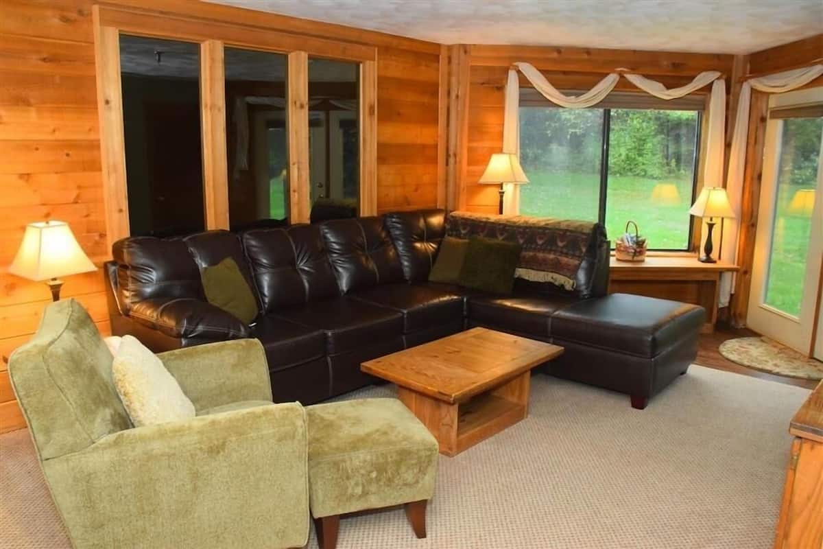 A cozy living room with a leather sofa, a green armchair, and a wooden coffee table.