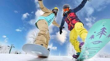 Deux snowboardeurs en mouvement sur une pente enneigée, sous un ciel dégagé.