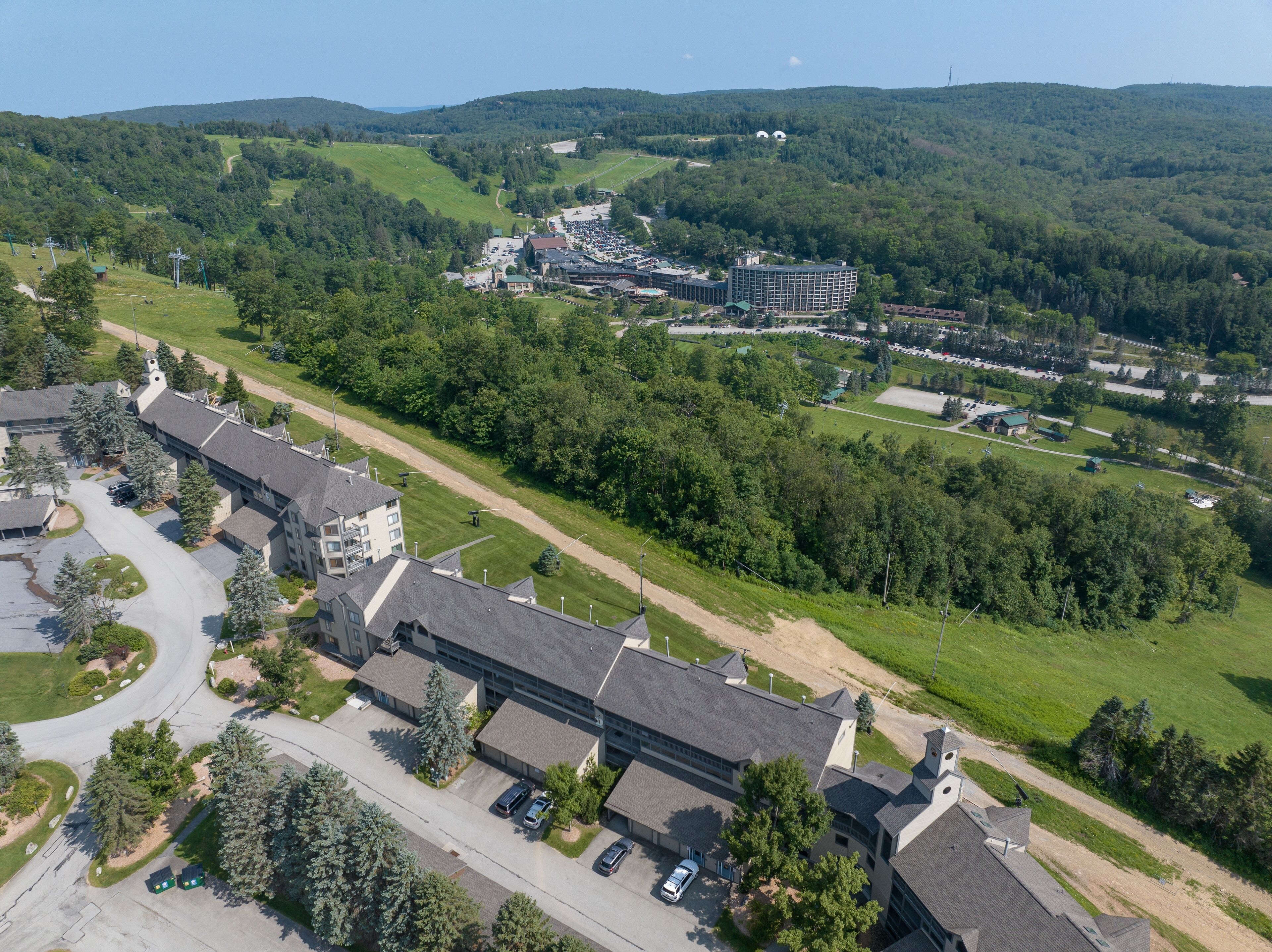 Eine Luftaufnahme eines Campus mit mehreren Gebäuden, Parkplätzen und umliegenden grünen Hügeln.