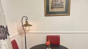 Ein Essbereich mit einem runden Tisch, roten Stühlen, einer Stehlampe und einem gerahmten Bild an der Wand.