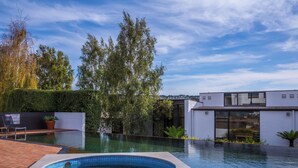 A modern outdoor swimming pool with a hot tub, surrounded by a landscaped garden and a contemporary building. - Waurn Ponds Estate (Waurn Ponds)