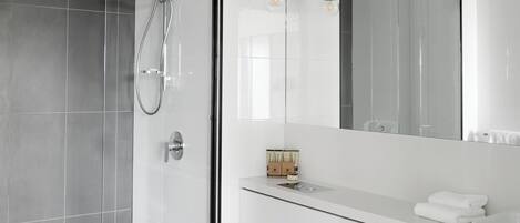 A modern bathroom with a white vanity, a glass shower enclosure, and a large mirror.