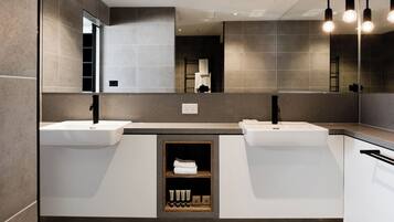 A modern bathroom with two sinks, a mirror, and a shelf with toiletries.