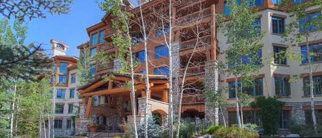 A multi-story hotel with stone and wood exterior, balconies, and a landscaped courtyard.