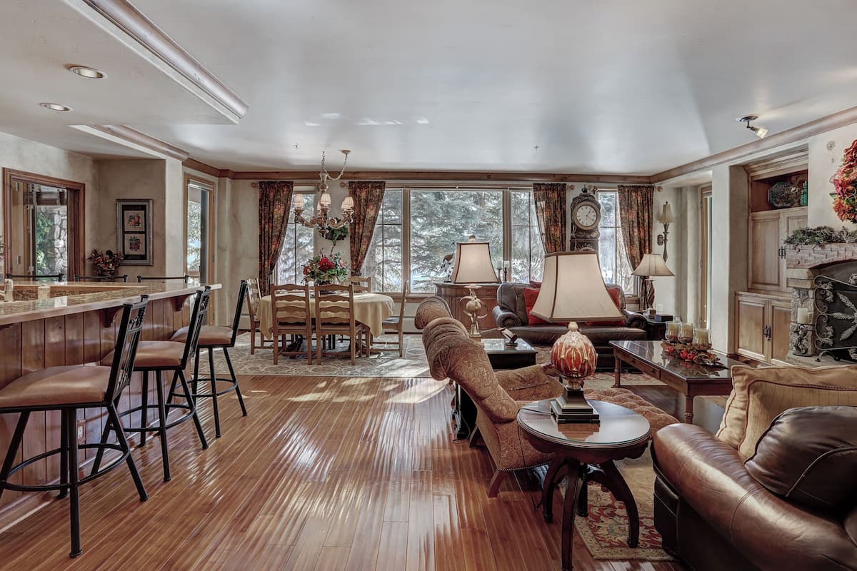 A spacious living room with a wooden floor, a dining area with a bar, and a fireplace.