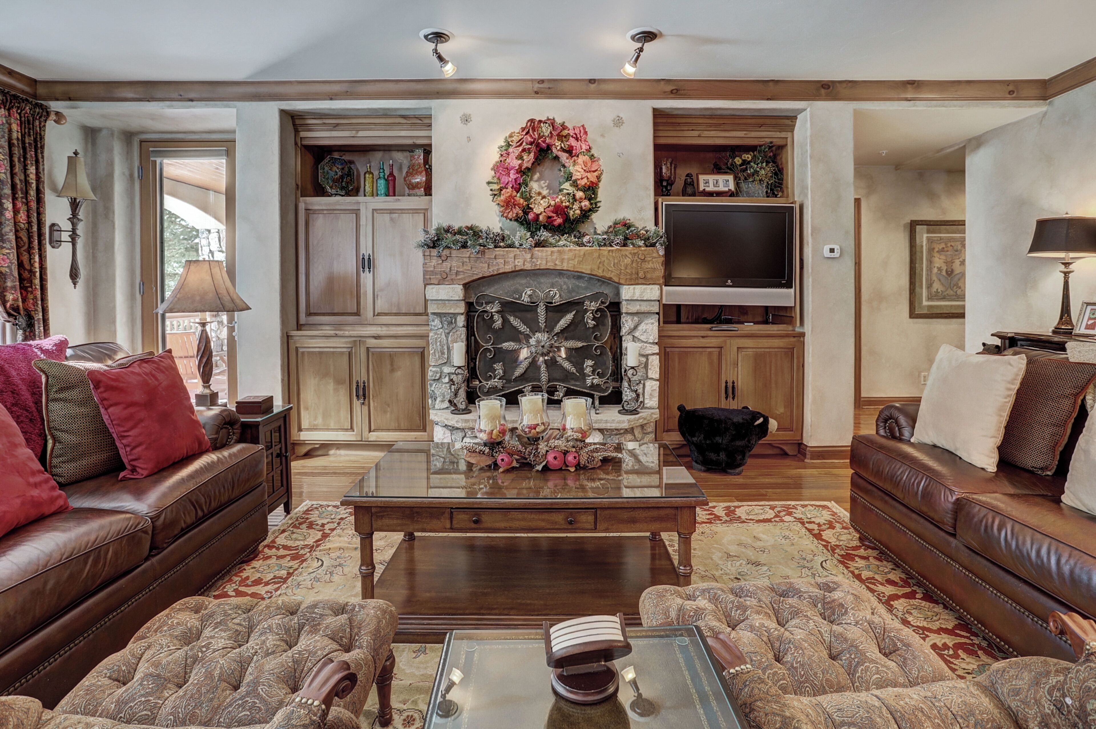 A cozy living room with a fireplace, leather sofas, and a television.