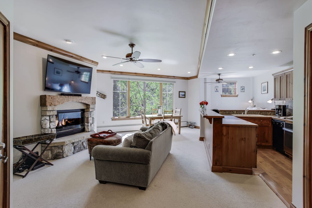 A spacious living room with a fireplace, a television, and a dining area with a wooden table and chairs.