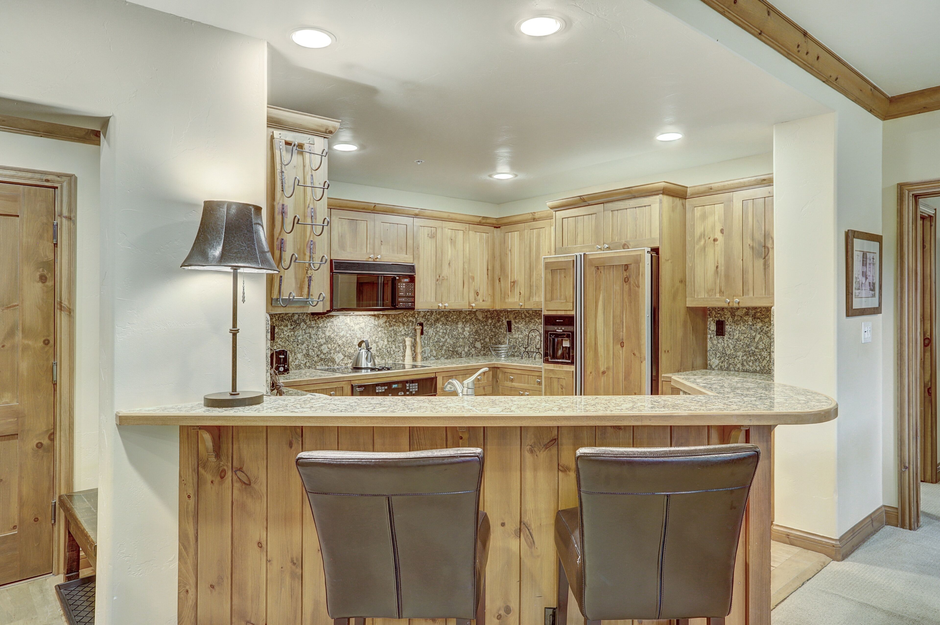 A kitchen with wooden cabinets, a central island with bar stools, and built-in appliances.