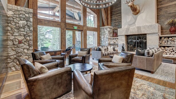 A spacious lobby with leather sofas, a stone wall, a fireplace, and a mounted deer head. - Beaver Creek Resort (Avon)