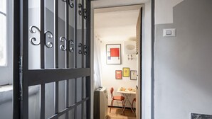 A room with a modern design, featuring a black metal gate, a small table with chairs, and a wall-mounted air conditioner. - GuestHost - Urban Nest - Comfy Studio in the Heart of Bari (Bari)