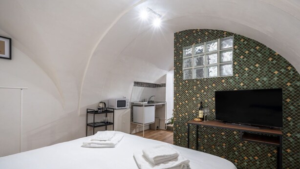 A compact room with a bed, a TV, a small kitchenette, and a bathroom. - GuestHost - Urban Nest - Comfy Studio in the Heart of Bari (Bari)